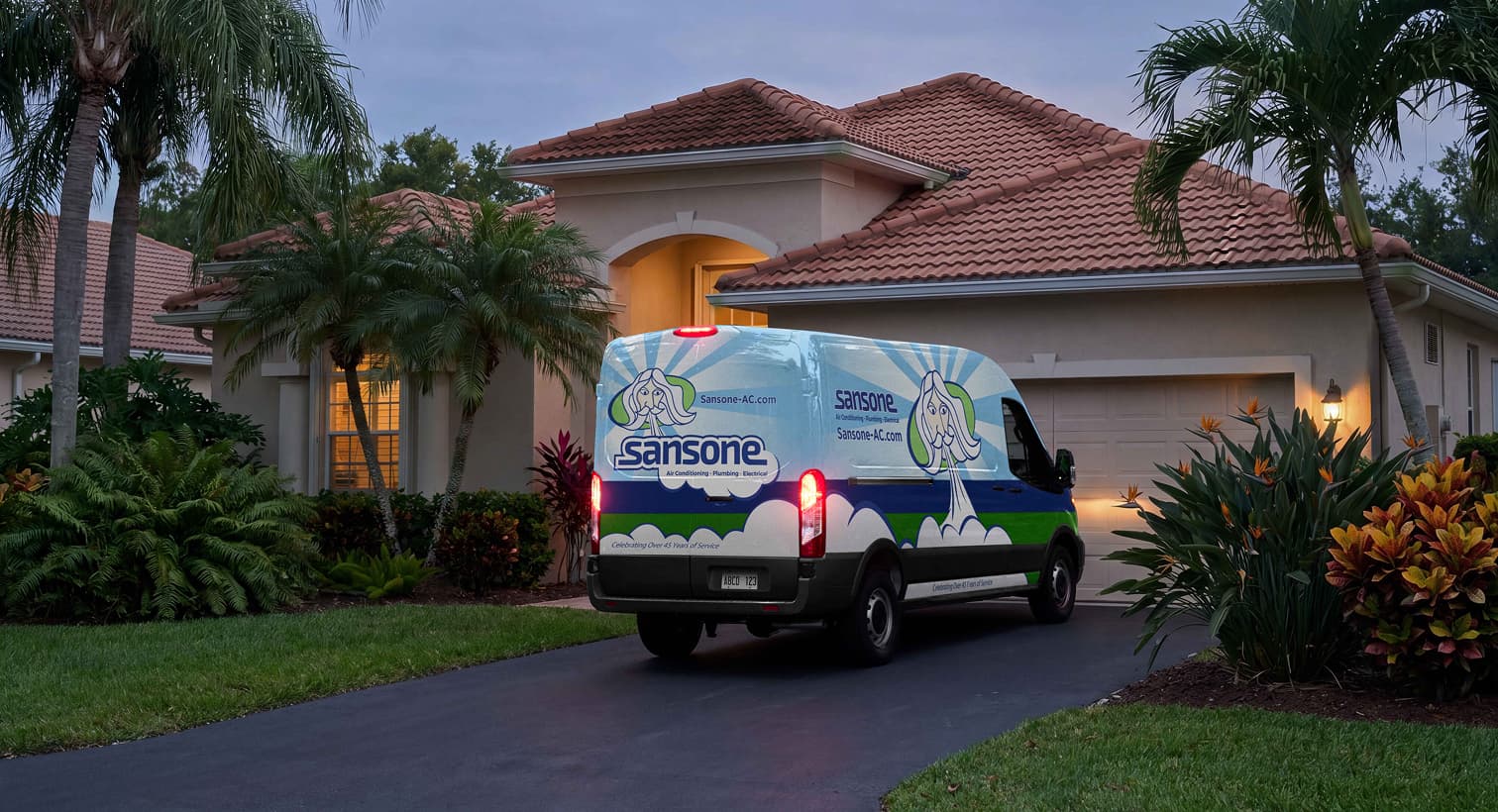 A Sansone service van parked in a residential driveway at dusk, arriving to provide emergency AC repair services.