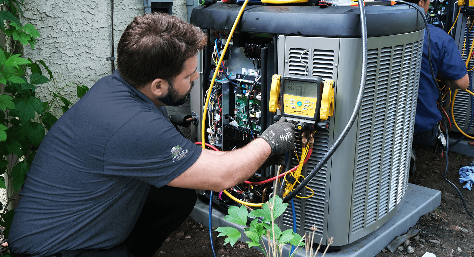 HVAC technician performing diagnostics on an outdoor residential heating and cooling unit.
