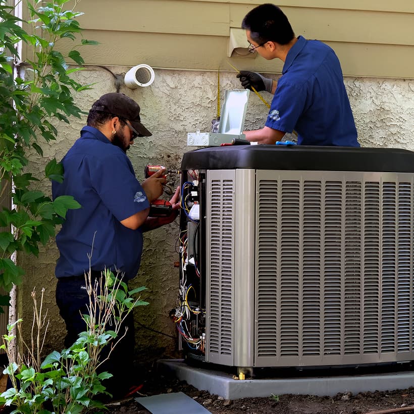 Two Sansone HVAC technicians installing a brand-new residential outdoor air conditioning condenser unit during a home AC replacement service.