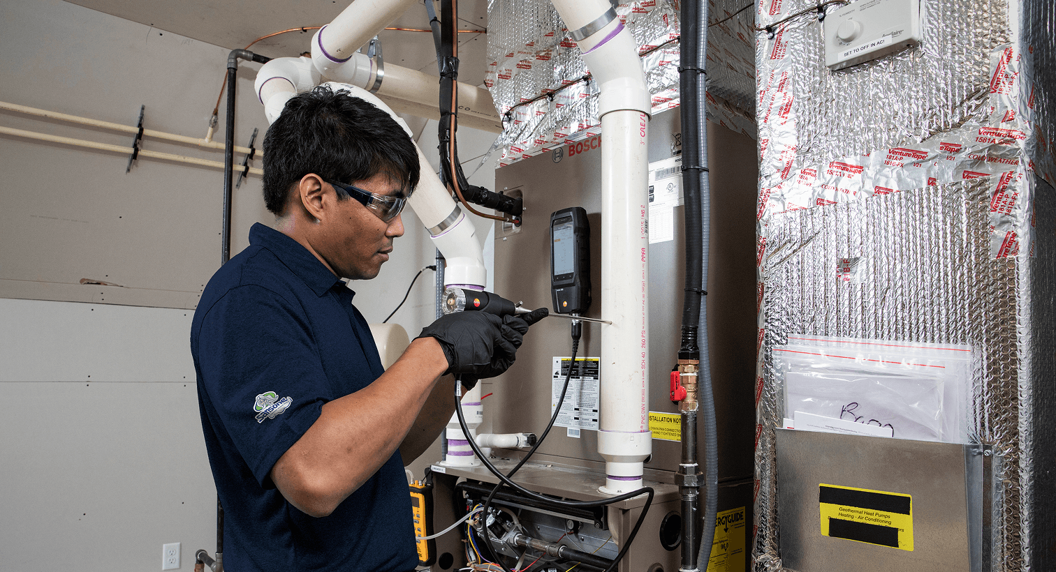 HVAC technician inspecting a residential furnace using diagnostic equipment.
