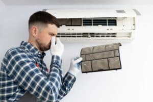 hvac technician fixing a smelly ac unit